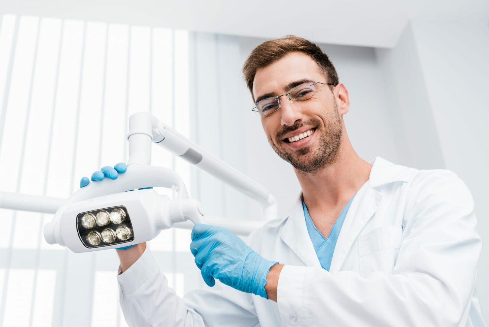 Smiling male dentist adjusting dental light