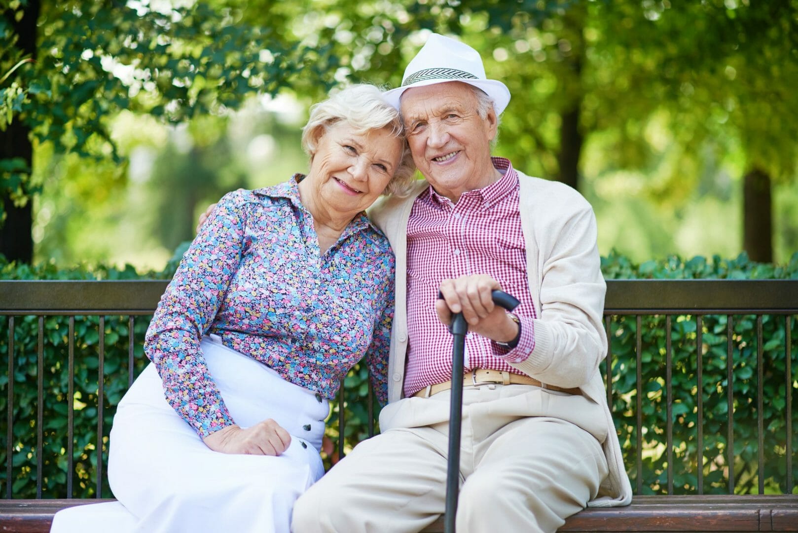 Elderly couple sitting on bench, smiling outdoors