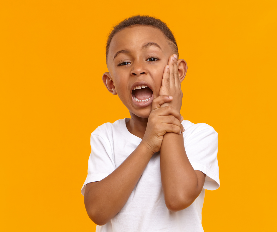 Boy with toothache holding his cheek, orange background